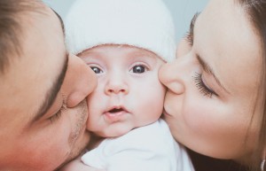 couple kissing baby on the cheek