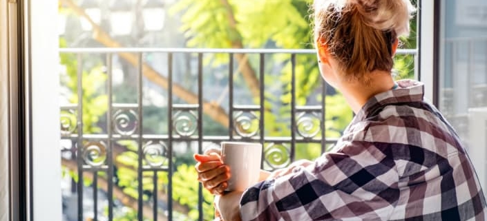 Woman looking out of window with coffee